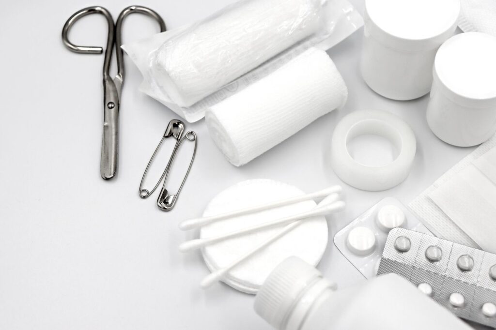 automotive A detailed flat lay of essential first aid supplies including bandages, scissors, and pills.