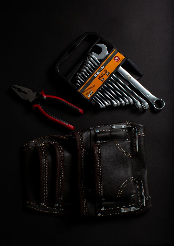 automotive Premium hand tools and leather tool belt arranged on a dark surface. Ideal for projects.