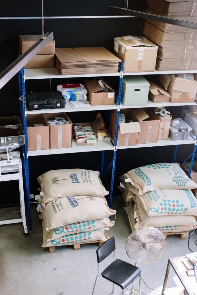 Organized warehouse with shelves filled with supplies and large sacks stored below.